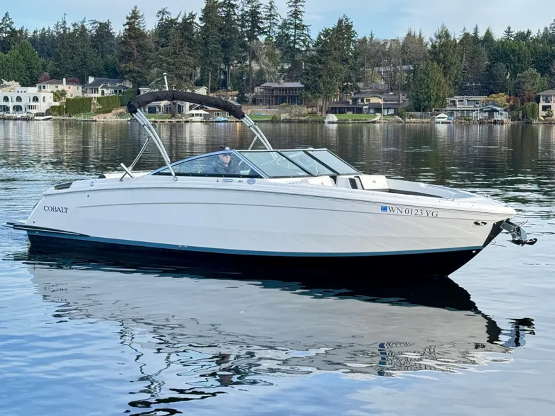 Slide: The Image of 2023 Cobalt R8 boat on a serene lake with waterfront homes and trees in the background. - 24