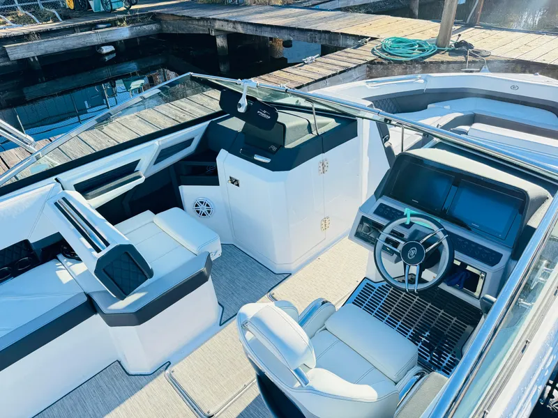 Slide: The Image of 2023 Cobalt R8 boat interior with modern dashboard and seating at a dock. - 3