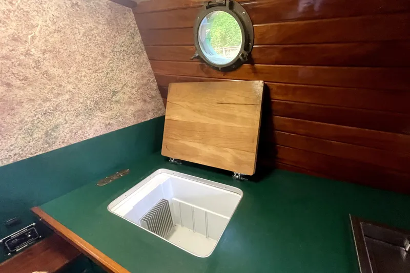 Slide: The Image of Wood-paneled boat kitchen with porthole, featuring a sink and cutting board, Rover Marine Lines 1995. - 24