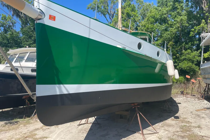 Slide: The Image of Green and white 1995 Bonny Rover boat on dry dock, surrounded by trees. - 3