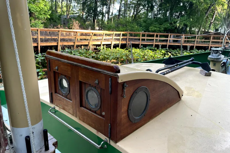 Slide: The Image of 1995 Bonny Rover boat deck with wooden hatch and portholes, surrounded by lush greenery. - 37