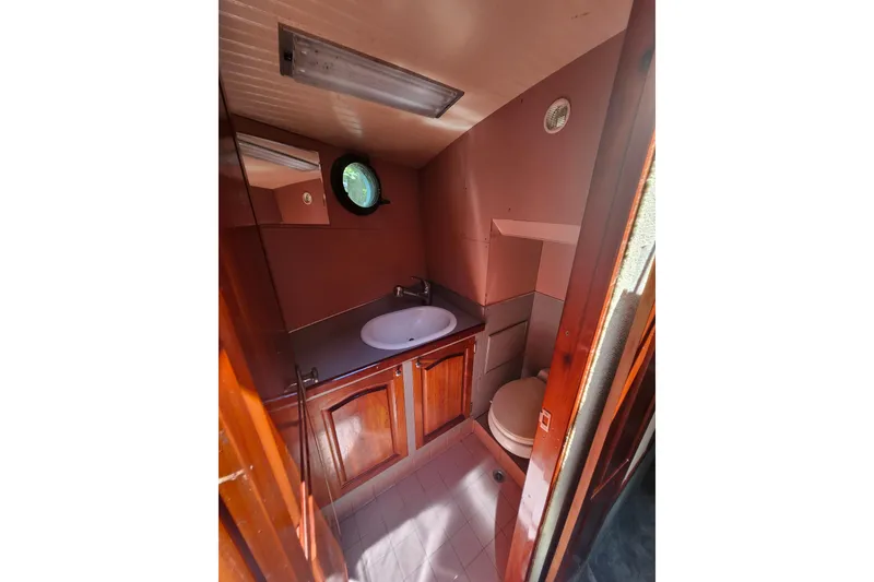 Slide: The Image of 1995 Rover Marine Lines Bonny Rover boat bathroom with wooden cabinets and round porthole window. - 41