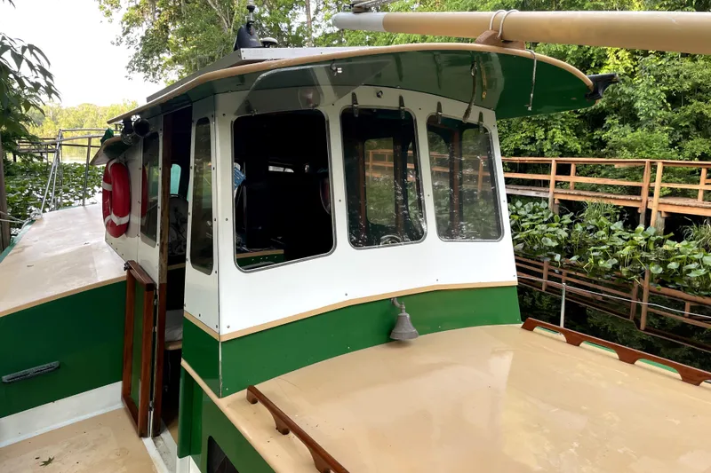 Slide: The Image of 1995 Bonny Rover boat with green and white cabin, docked near lush greenery. - 5