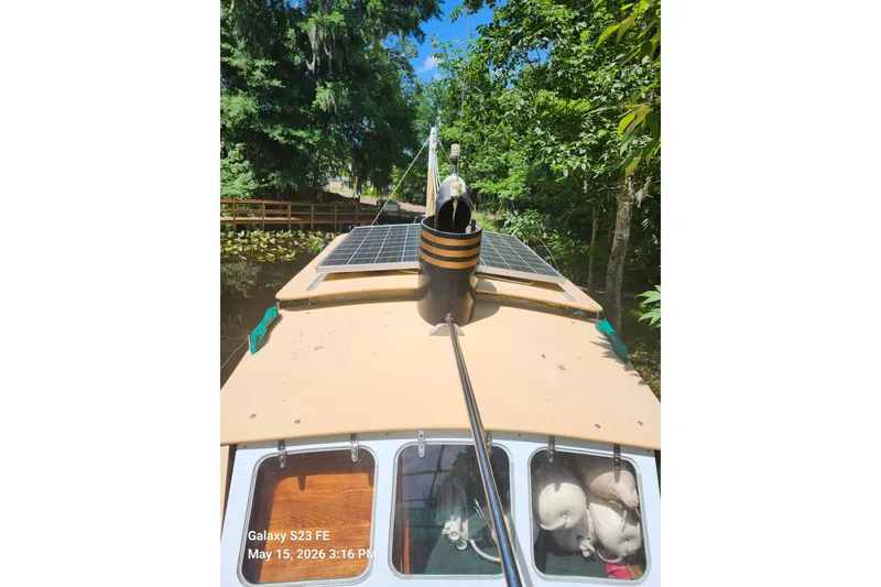 Slide: The Image of 1995 Bonny Rover boat with solar panels cruising through a lush, tree-lined waterway. - 59