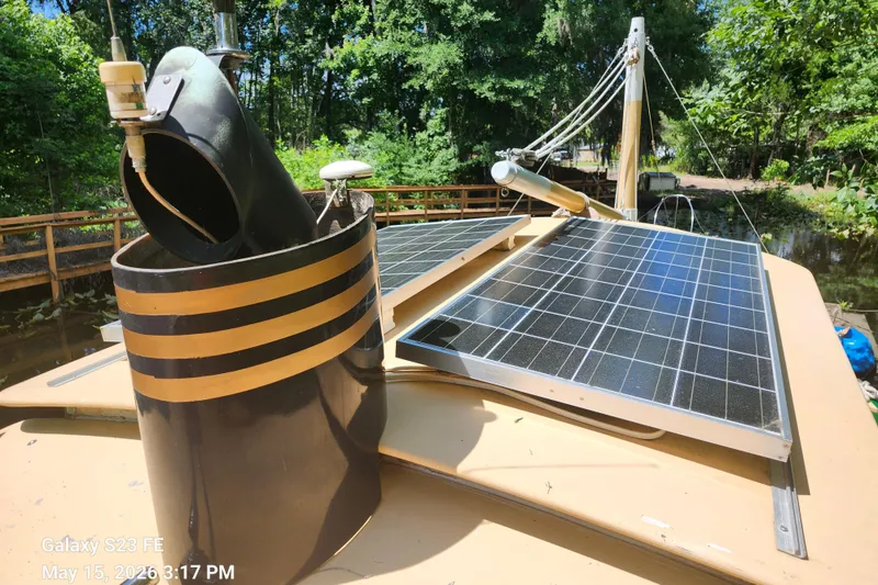 Slide: The Image of Rover Marine Lines Bonny Rover 1995 with solar panels on deck, surrounded by lush greenery. - 60
