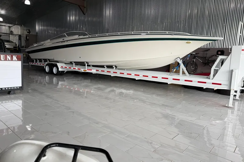 The Image of 2000 Fountain 47 Lightning boat on trailer in a polished indoor garage setting. - 1
