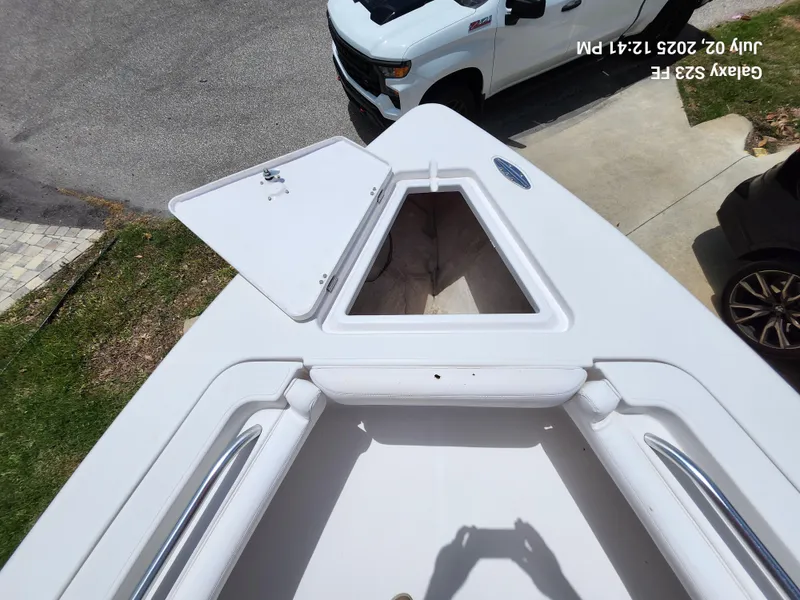 Slide: The Image of 2010 Donzi 29ZF boat deck with open storage compartment, parked near a white truck. - 22