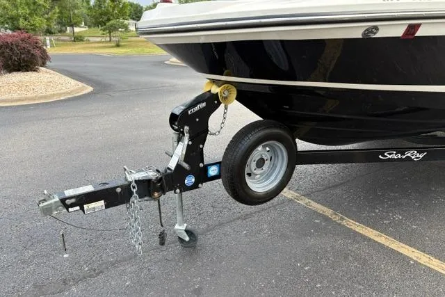 Slide: The Image of 2017 Searay SPX210 boat on trailer, parked on asphalt, featuring black hull and trailer hitch. - 14