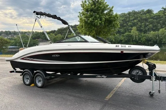 Slide: The Image of 2017 Searay SPX210 boat on trailer, parked near a scenic lake with lush greenery. - 3