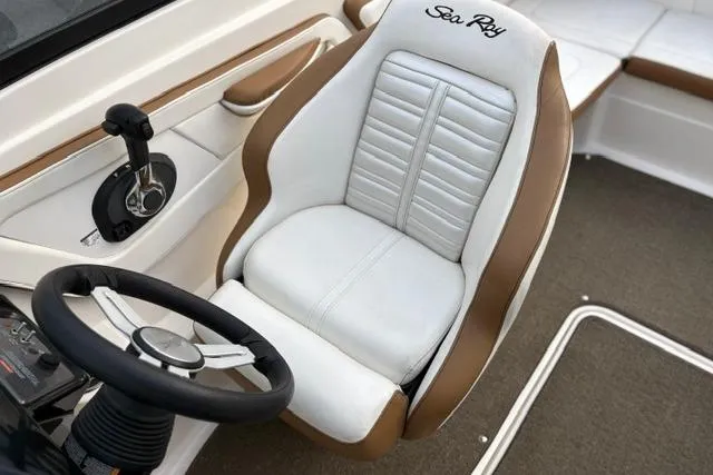 Slide: The Image of 2017 Searay SPX210 boat interior with white and brown captain's seat and steering wheel. - 45