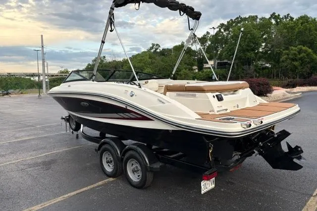 Slide: The Image of 2017 Searay SPX210 boat on trailer in parking lot, surrounded by trees. - 6