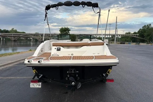 Slide: The Image of 2017 Searay SPX210 boat on trailer, parked near a river with a scenic bridge view. - 7