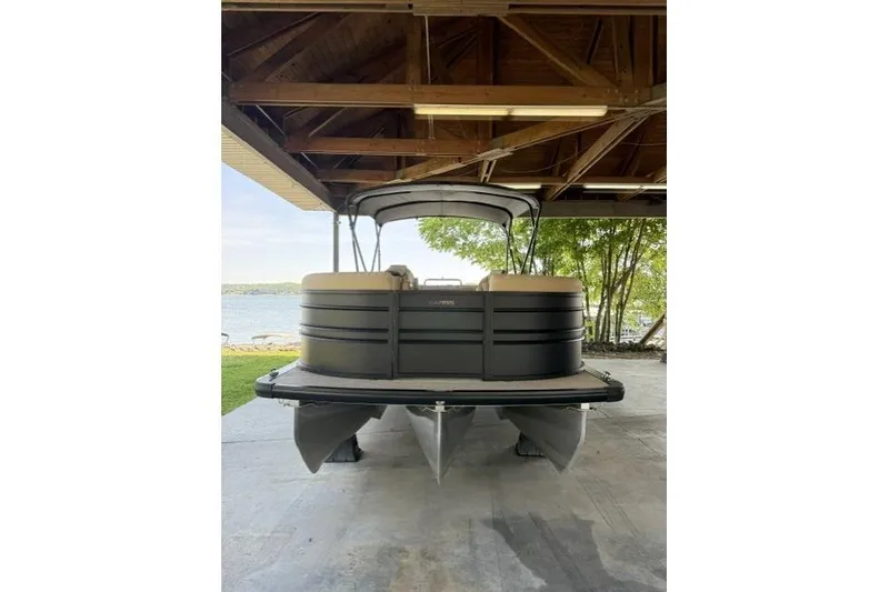 Slide: The Image of 2025 Harris Sunliner 230 pontoon boat under a wooden shelter by a lake. - 11