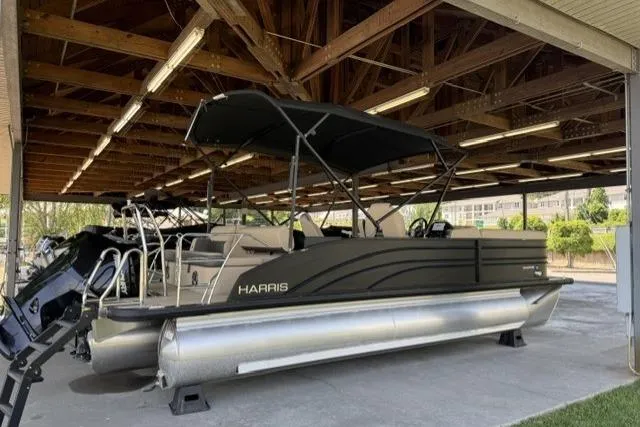 Slide: The Image of 2025 Harris Sunliner 230 pontoon boat under wooden shelter, featuring sleek design and modern amenities. - 4