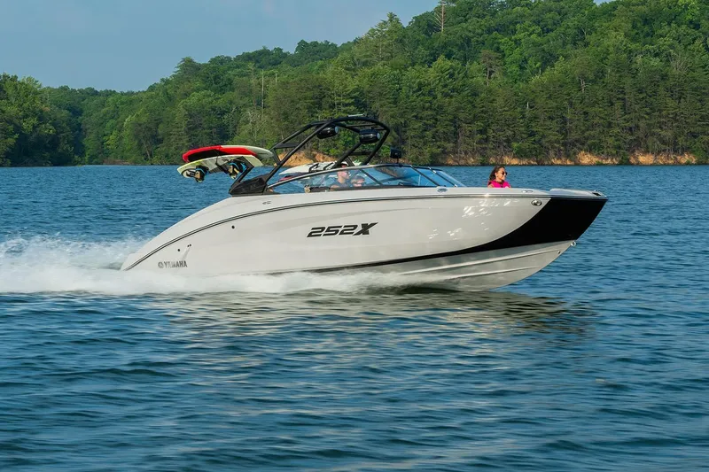 Slide: The Image of Manufacturer Provided Image: 2026 Yamaha Boats 252XE cruising on a scenic lake with lush green forest backdrop. - 2