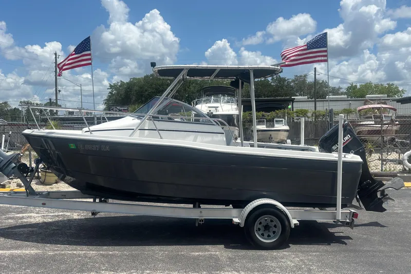 The Image of 1994 Trophy 1802 Walkaround boat on trailer, American flags in background, sunny day. - 1