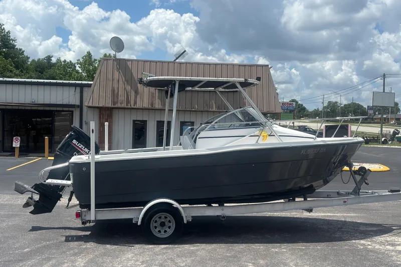 Slide: The Image of 1994 Trophy 1802 Walkaround boat on trailer, parked outside a building under cloudy skies. - 6