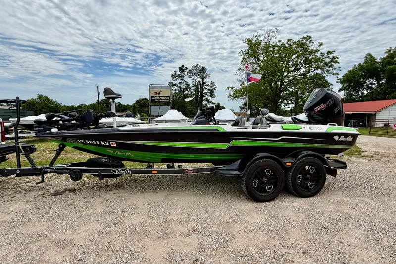 Slide: The Image of 2023 BassCat Erya boat with green accents on a trailer, parked outdoors. - 1