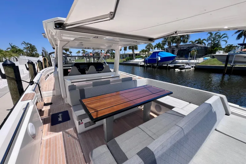 Slide: The Image of Luxurious 2022 Windy SR 44 BLACKHAWK yacht with elegant seating and wooden table, docked by a serene waterfront. - 30
