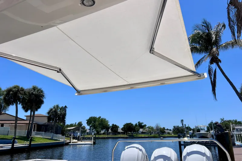 Slide: The Image of 2022 Windy SR 44 BLACKHAWK boat with sunshade, docked near palm trees and waterfront homes. - 31
