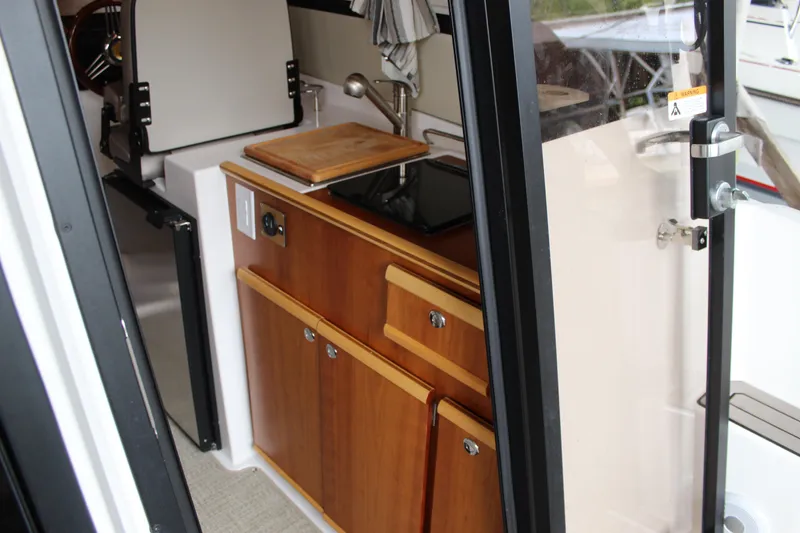 Slide: The Image of 2024 Cutwater C-248 Coupe interior kitchen with wooden cabinetry and compact design. - 14