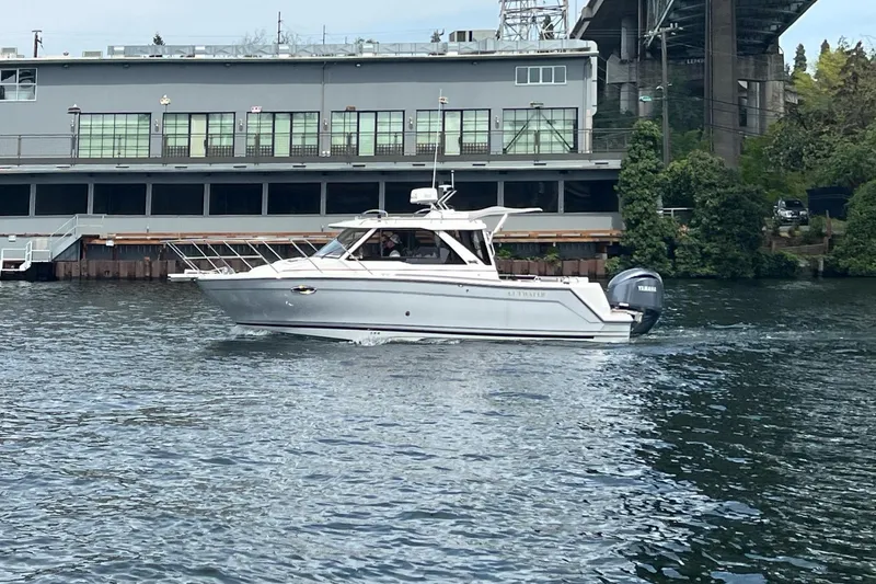 Slide: The Image of 2024 Cutwater C-248 Coupe cruising on a river near an industrial building. - 2