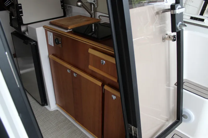 Slide: The Image of 2024 Cutwater C-248 Coupe interior kitchen with wooden cabinets and modern appliances. - 7