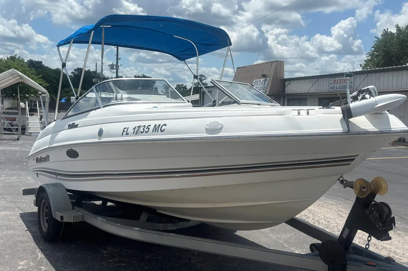 Slide: The Image of 2002 Wellcraft 180 Sportsman boat on trailer with blue canopy, parked outdoors. - 6
