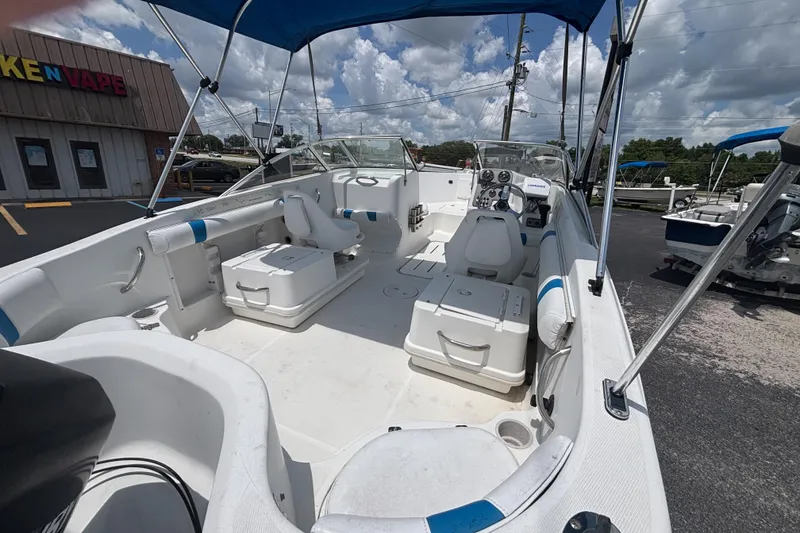 Slide: The Image of 2002 Wellcraft 180 Sportsman boat with blue canopy, parked outdoors under a cloudy sky. - 8