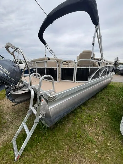Slide: The Image of 2013 Bennington 20SLMX pontoon boat with Yamaha motor, parked on grass. - 2