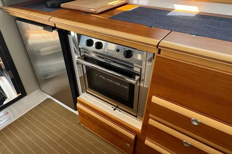 Slide: The Image of 2020 Cutwater C-30 CB yacht kitchen with stainless steel oven and wooden cabinetry. - 13