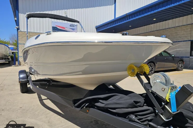 Slide: The Image of 2023 Stingray 182 SC boat on trailer, parked outside a building under clear blue sky. - 17