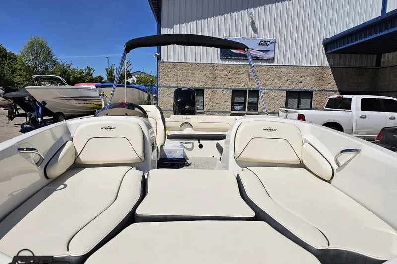 Slide: The Image of 2023 Stingray 182 SC boat with spacious seating, parked outdoors near a building. - 19