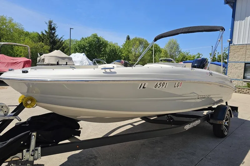 Slide: The Image of 2023 Stingray 182 SC boat on trailer, parked outdoors under clear blue sky. - 21