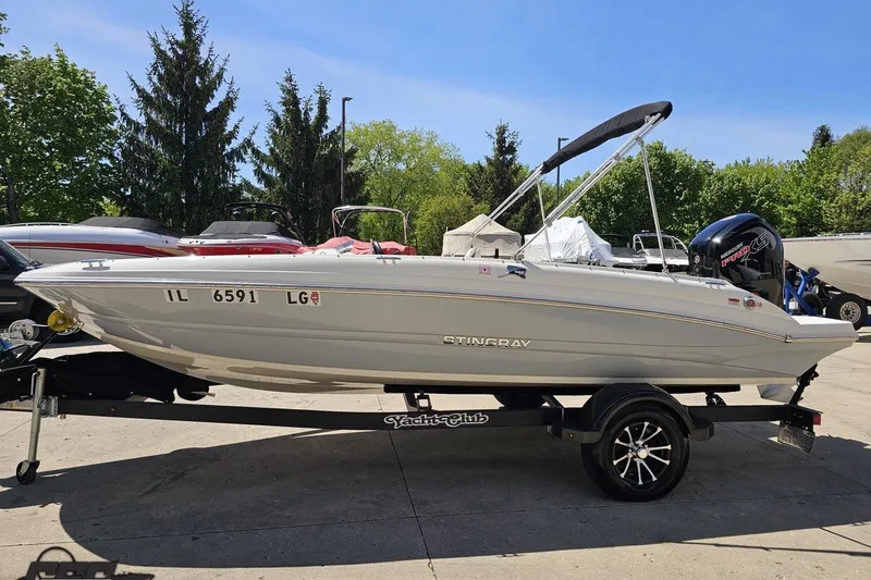 Slide: The Image of 2023 Stingray 182 SC boat on trailer, parked outdoors under clear blue sky. - 23