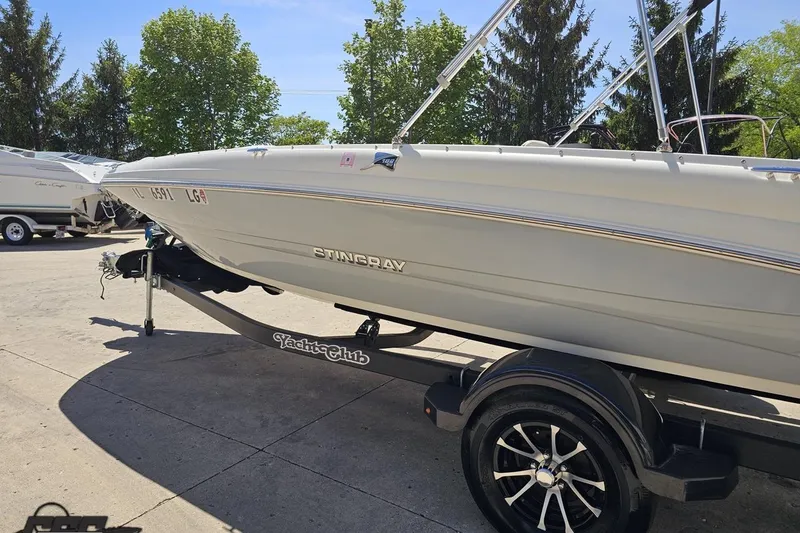 Slide: The Image of 2023 Stingray 182 SC boat on trailer, parked outdoors with trees in background. - 25