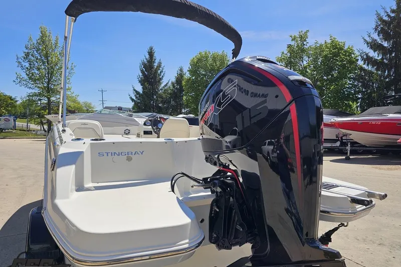 Slide: The Image of 2023 Stingray 182 SC boat with powerful outboard motor, parked outdoors on a sunny day. - 30
