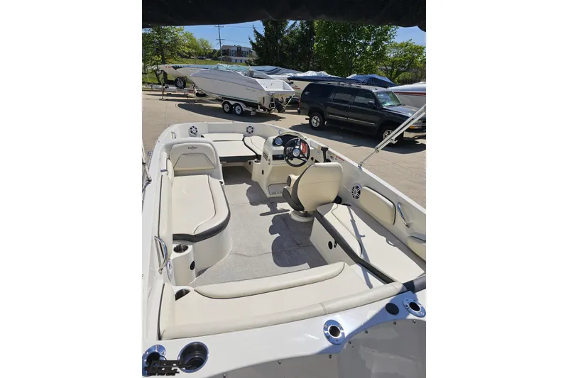 Slide: The Image of 2023 Stingray 182 SC boat interior with seating and steering wheel, parked outdoors. - 37