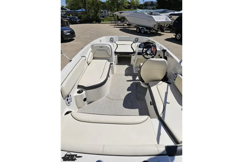 Slide: The Image of 2023 Stingray 182 SC boat interior with seating and steering wheel, parked outdoors. - 39