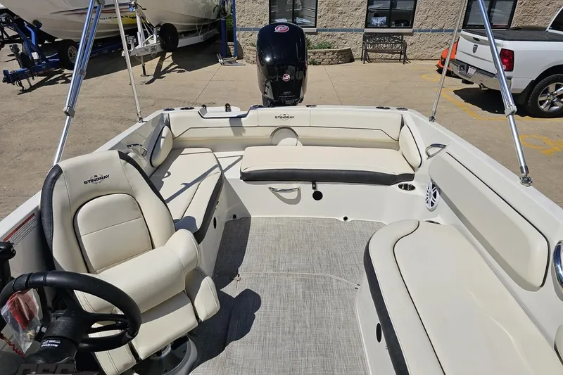 Slide: The Image of 2023 Stingray 182 SC boat interior with seating and steering wheel, parked outdoors. - 75
