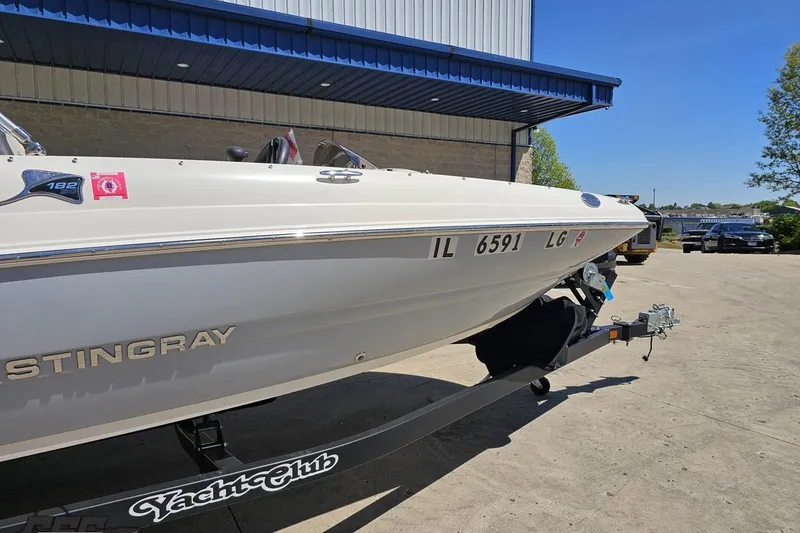 Slide: The Image of 2023 Stingray 182 SC boat on trailer outside a building under clear blue sky. - 8