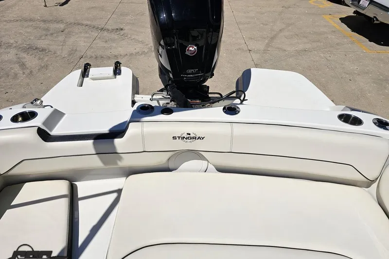 Slide: The Image of 2023 Stingray 182 SC boat interior with motor, featuring white seating and cup holders. - 83