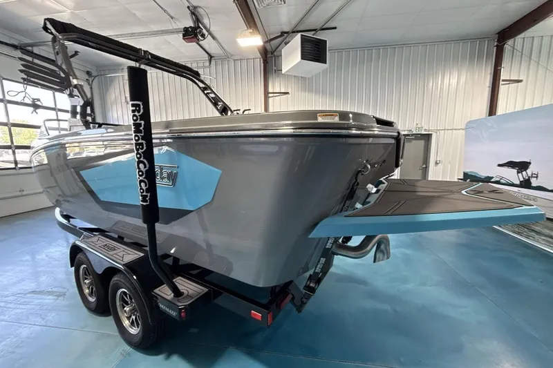 Slide: The Image of 2024 Heyday WTSurf boat in showroom, featuring sleek design and dual-axle trailer. - 3