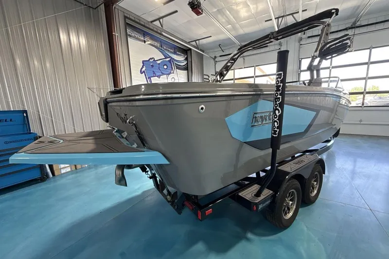 Slide: The Image of 2024 Heyday WTSurf boat in showroom, featuring sleek design and dual-axle trailer. - 5