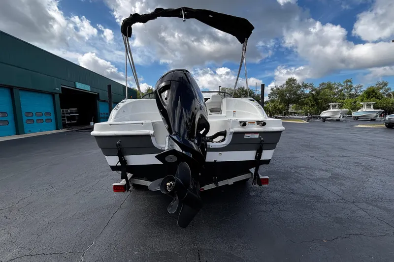 Slide: The Image of 2022 Hurricane SunDeck 217 OB boat with outboard motor, parked outdoors under a cloudy sky. - 3
