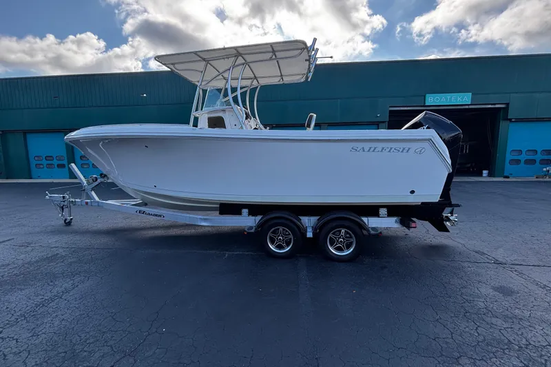 Slide: The Image of 2022 Sailfish 242 CC boat on trailer, parked outside a warehouse. - 3