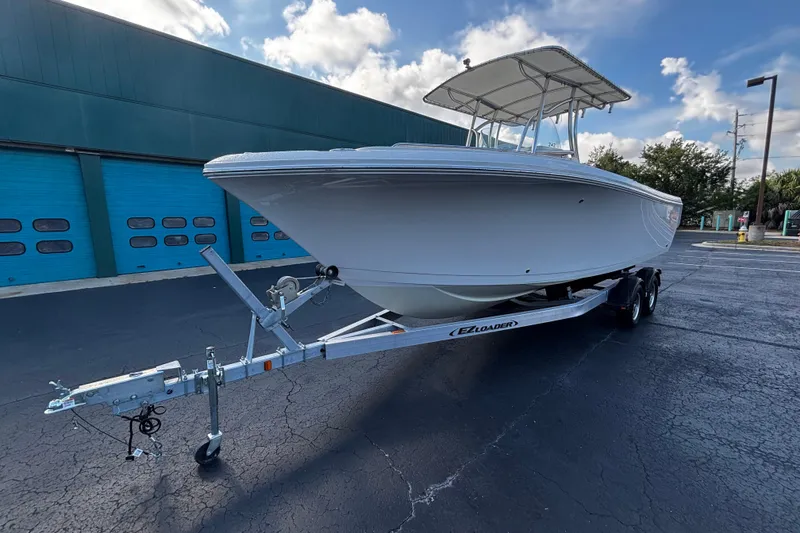 Slide: The Image of 2022 Sailfish 242 CC boat on trailer, parked outdoors under a blue sky. - 4