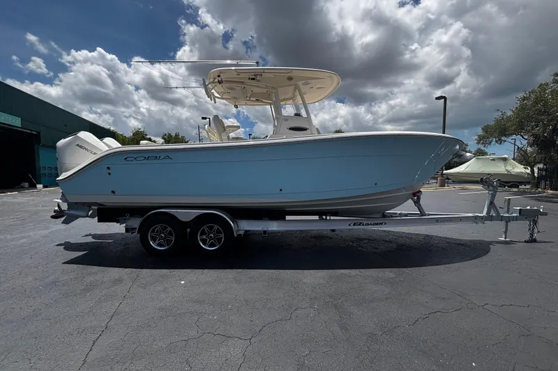 The Image of 2023 Cobia 262 Center Console boat on trailer under cloudy sky. - 1
