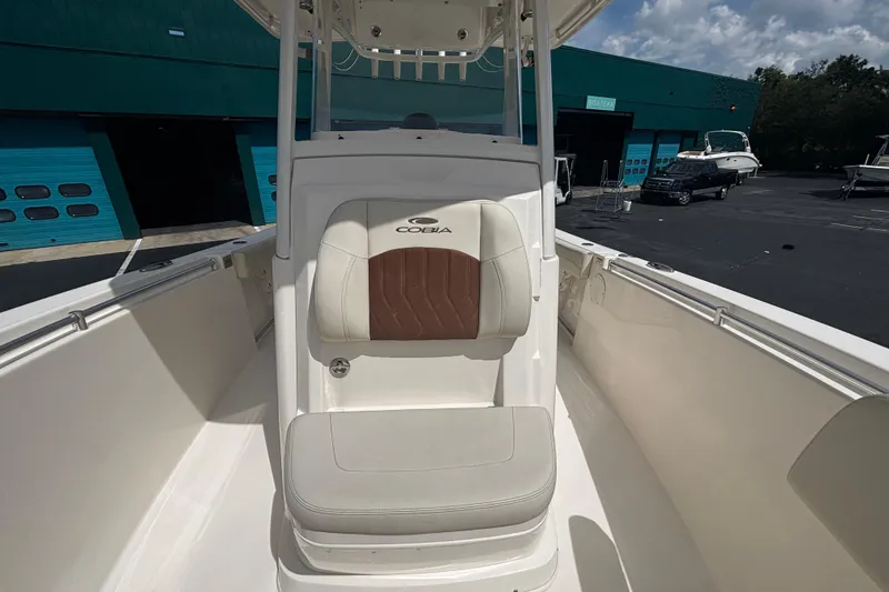 Slide: The Image of 2023 Cobia 262 Center Console boat interior with cushioned seating, docked near blue garage doors. - 4