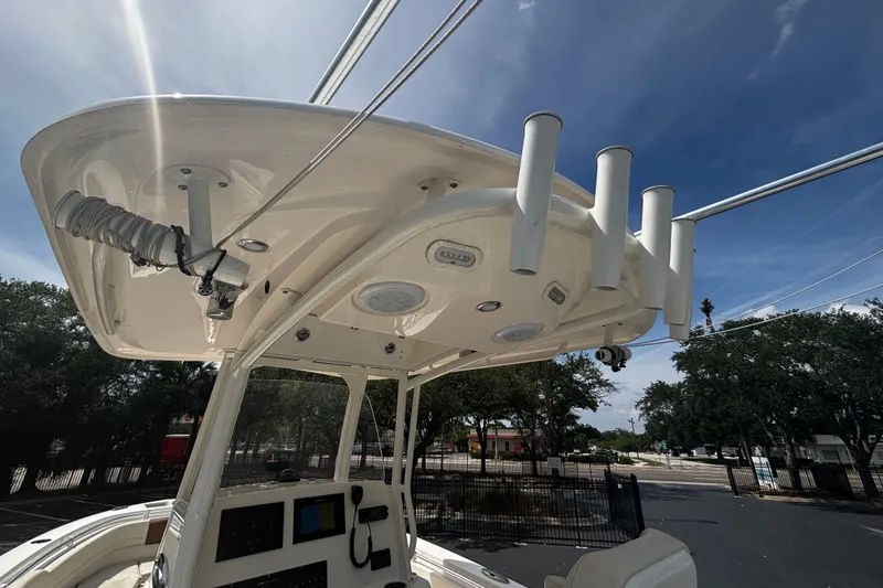 Slide: The Image of 2023 Cobia 262 Center Console boat with T-top and rod holders under a clear sky. - 6